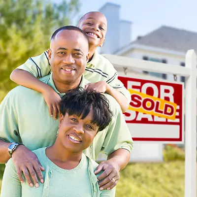 Image of family in front of SOLD real estate sign